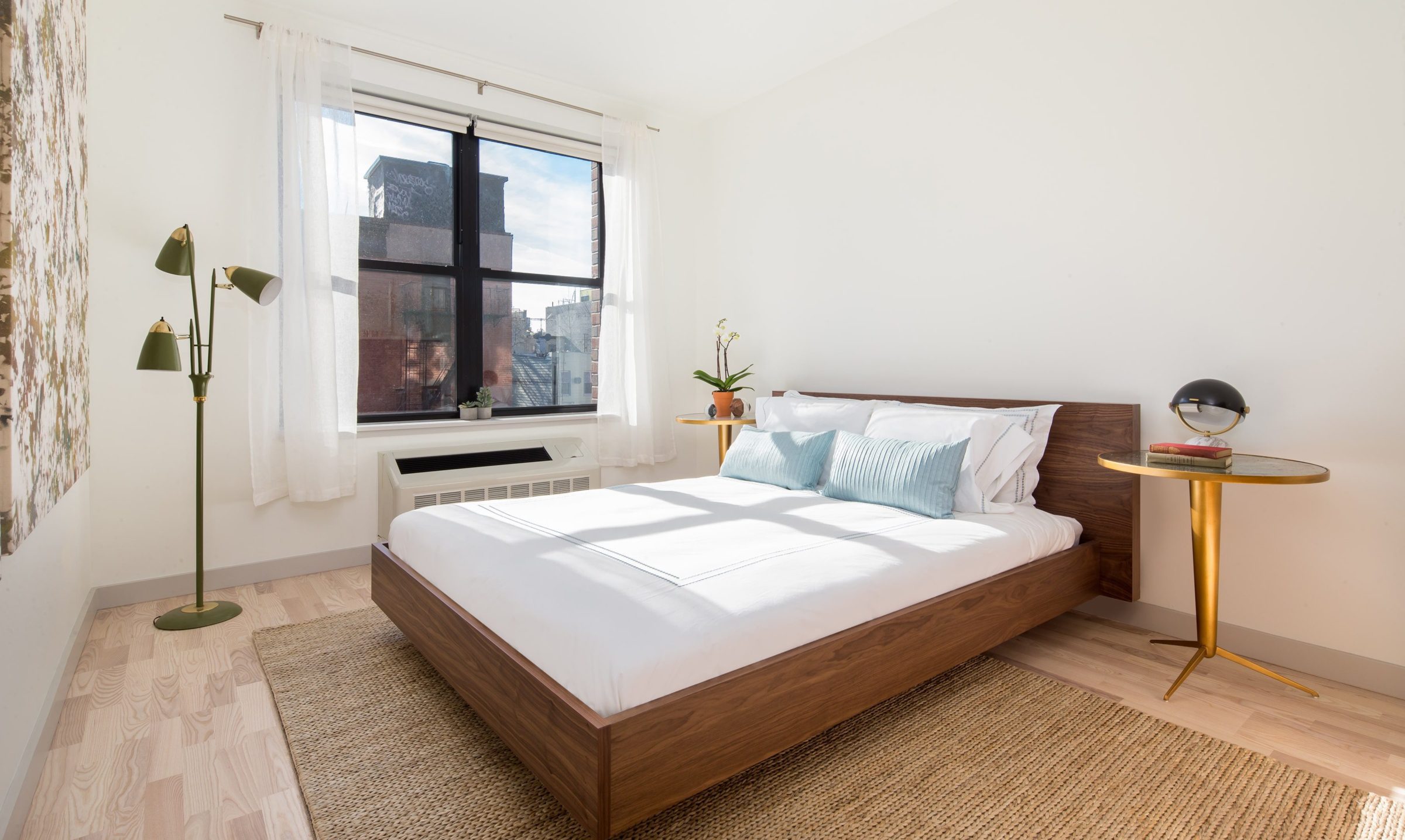 Bedroom with white walls, large window, and stylish furniture